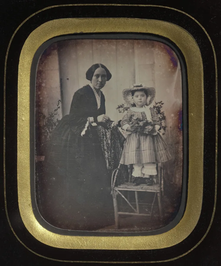 Child Standing on a Chair Holding Flowers, with Mother